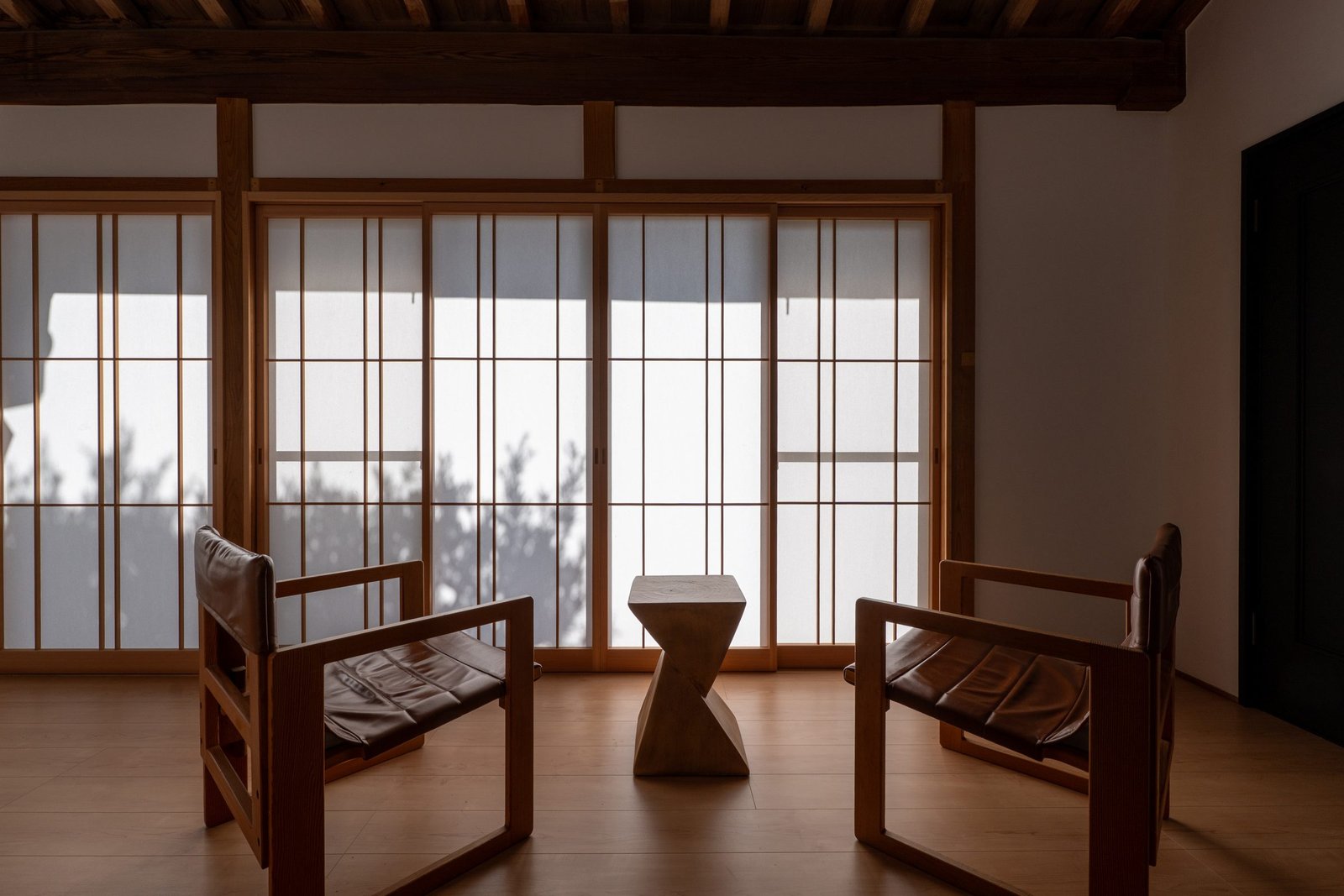 障子越しの光が差す部屋に置かれた、木の肘掛け椅子